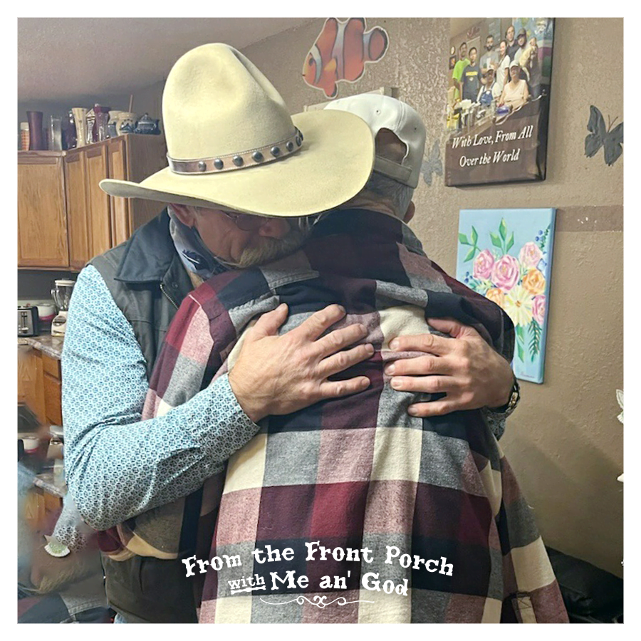 A cowboy hugs another man. A text overlay on the image says "From the Front Porch with Me an' God".